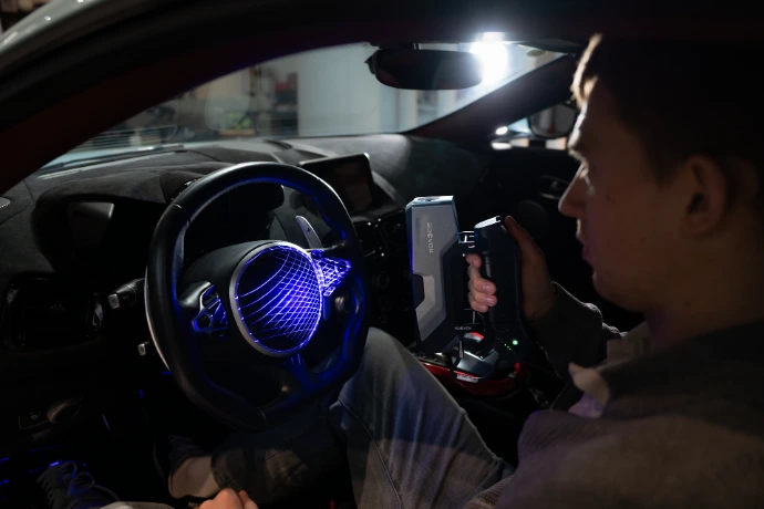 Professionnel de l'automobile scannant un volant de voiture de sport avec son scanner sans fil