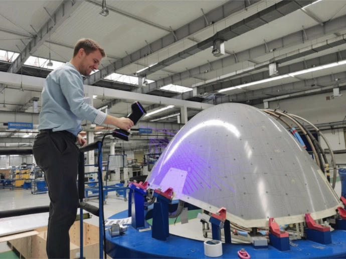 Un homme capturant une surface composite avec son scanner 3d Scanology fourni par Triskan